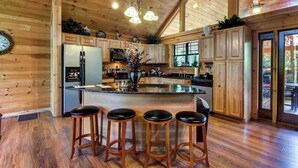 L’intérieur d’une cabane en bois comprend un îlot de cuisine, des tabourets de bar et une grande fenêtre.