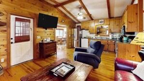 Interno di una baita di legno con soggiorno, cucina e zona pranzo.