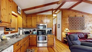 Cucina con mobili in legno, elettrodomestici in acciaio inossidabile e un divano in pelle rossa in un ambiente dallo stile chalet.