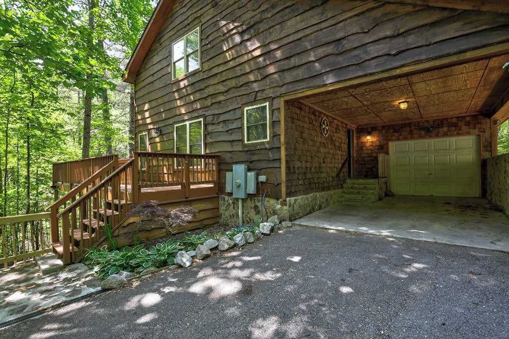 Une cabane en rondins avec une terrasse en bois, un garage et un mur en pierre.