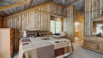 A bedroom with a wooden ceiling, a bed with a quilt, a dresser, and a window.