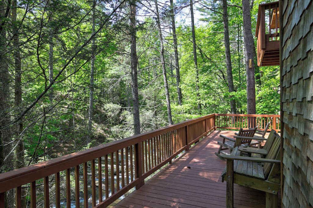Una terraza de madera con bancos, rodeada de un bosque.