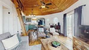 Un salon spacieux avec un plafond en bois, un canapé, une table basse et un téléviseur.