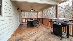 A covered porch with a grill, dining table, and chairs. - Alpine Retreat Stays (Helen)