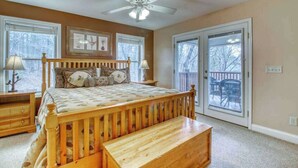 A bedroom with a wooden bed, a ceiling fan, and a view through a glass door. - Alpine Retreat Stays (Helen)
