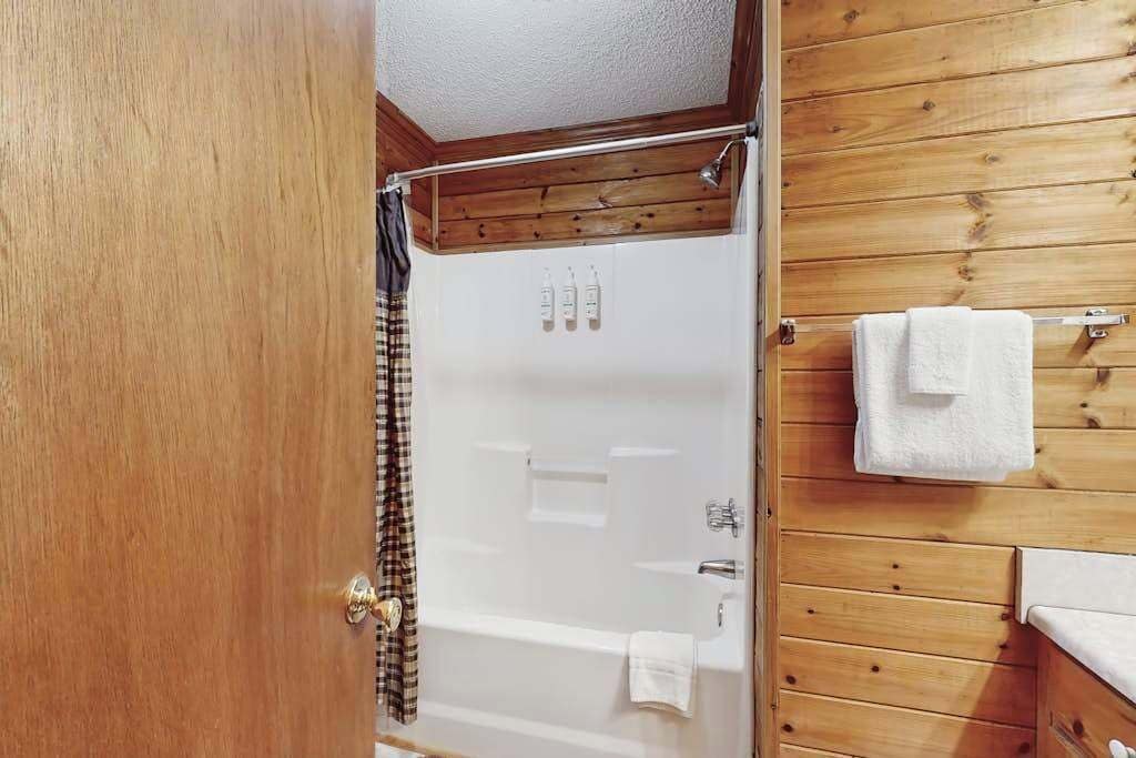 A wooden-paneled bathroom with a bathtub, a shower curtain, and a towel rack.