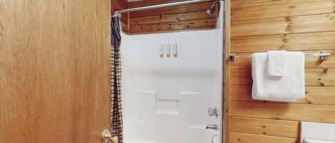 A wooden-paneled bathroom with a bathtub, a shower curtain, and a towel rack.