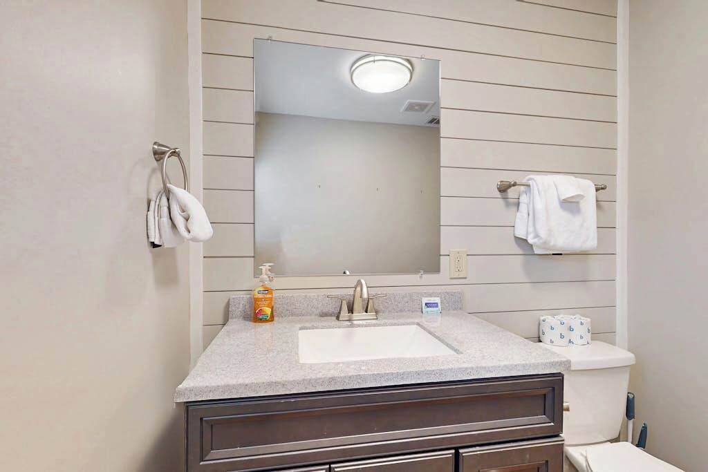 Ein Badezimmer mit Waschbecken, Spiegel, Handtuchhalter und Toilette.