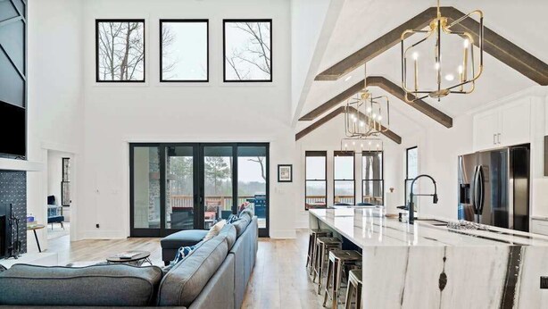 A spacious living area with a large sofa, a kitchen with a marble countertop, and a view through the glass doors. - Knight Mountain Stay (Ellijay)