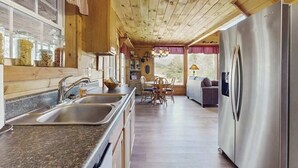 Ein Holzblockhaus-Interieur mit Küche, Essbereich und einem großen Kühlschrank.