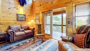 A wooden cabin interior with a leather sofa, a rocking chair, and a bear mounted on the wall. - Cherokee Sunrise Cabin (Mineral Bluff)