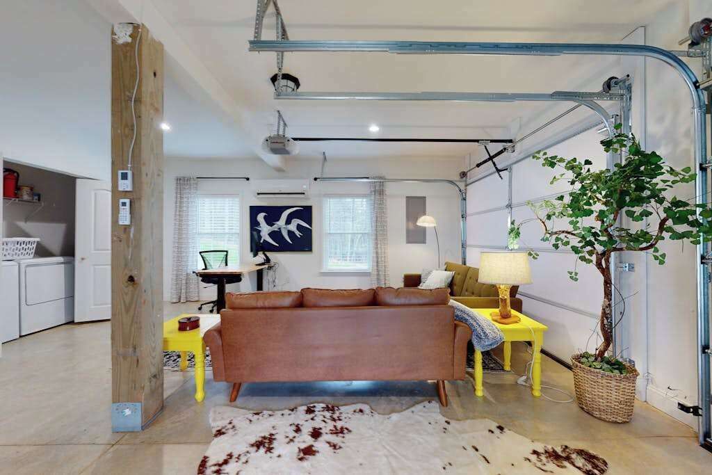A modern living room with a sofa, a small table, a lamp, and a potted plant.