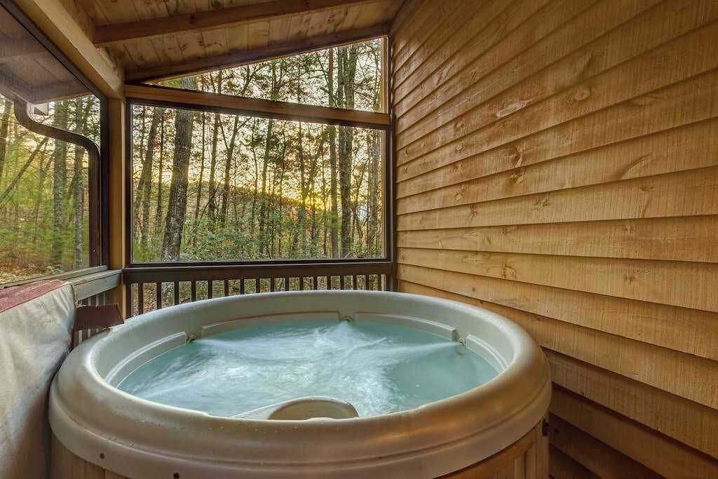 Un bain à remous dans un chalet en bois avec vue sur une forêt.
