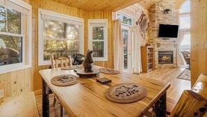 A wooden interior with a dining table, chairs, a fireplace, and a television. - House of Views Getaway (Blue Ridge)