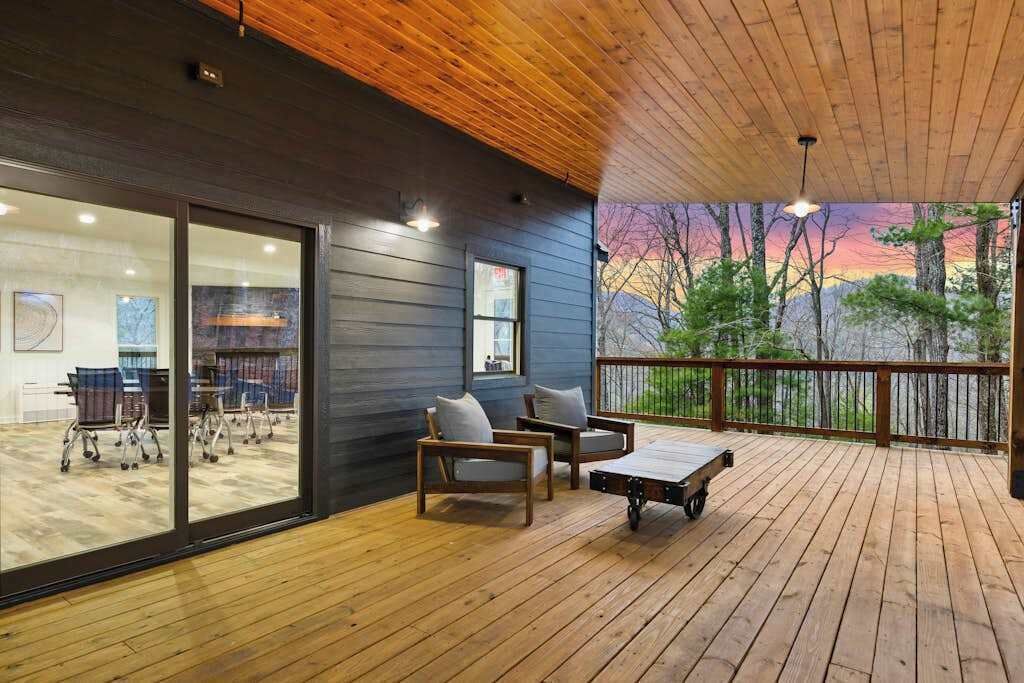 A wooden deck with outdoor seating and a view of trees.