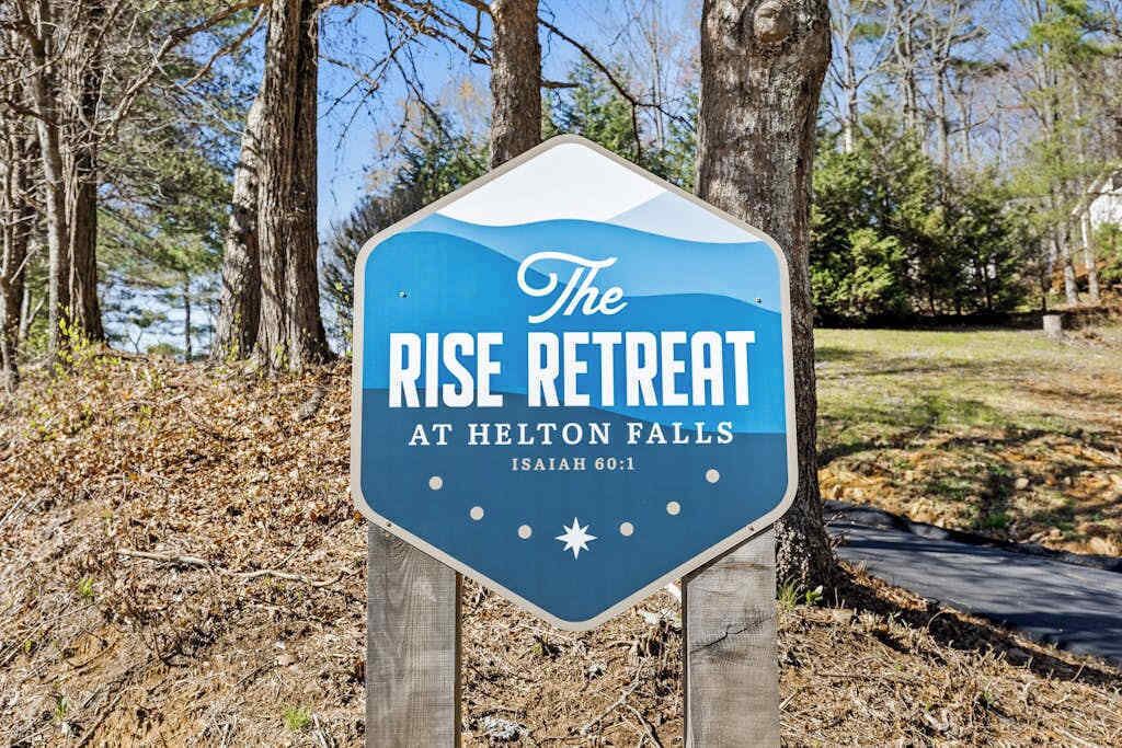 Señal de The Rise Retreat en Helton Falls, con un paisaje natural de fondo.