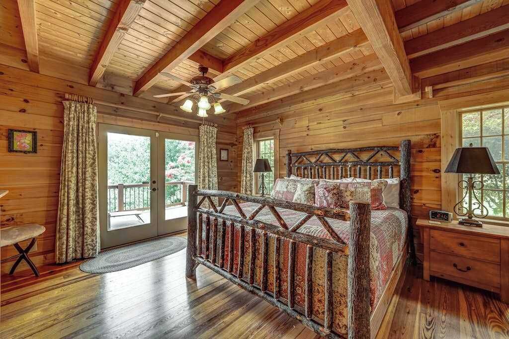 Camera da letto in una casetta di legno, con un letto, un comodino, una finestra e una porta che dà su un patio esterno.