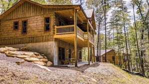Eine Holzhütte mit Balkon, umgeben von Bäumen.
