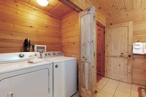 Ein Holzblockhaus-Interieur mit Waschmaschine, Trockner und einer Holztür.