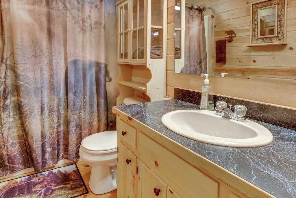 Ein Badezimmer im Chalet-Stil mit Holzeinrichtung, einem Marmorwaschbecken und einer Duschvorhang.