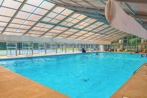 Una piscina interior con techo de cristal, zona de borde limpia y varias pistas.