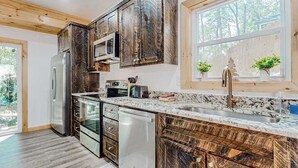 Eine moderne Küche mit Holzschränken, Edelstahlgeräten und einem großen Fenster mit Pflanzen.