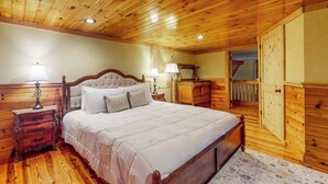 Une chambre aux murs lambrissés, avec un grand lit, des tables de chevet et une armoire.