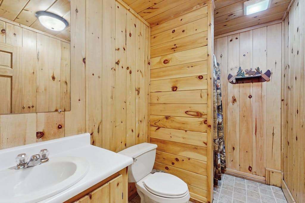 Un bagno in legno con lavandino, servizi igienici e zona doccia.