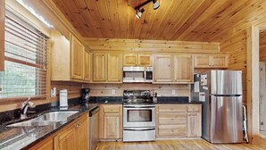 A wooden-paneled kitchen with a stainless steel refrigerator, oven, and microwave. - River Escape On The Toccoa River (Mineral Bluff)