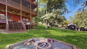 A wooden cabin with a deck, a fire pit, and a grassy yard. - River Escape On The Toccoa River (Mineral Bluff)