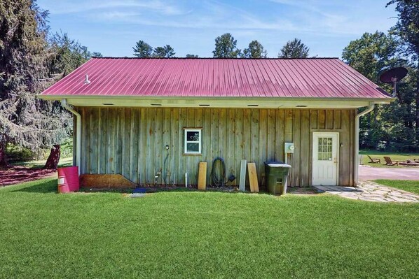 A small wooden shed with a red roof, a door, and a window.