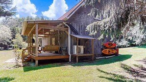 Eine rustikale Holzhütte mit Veranda, überdachter Sitzgelegenheit und einem Kanu.