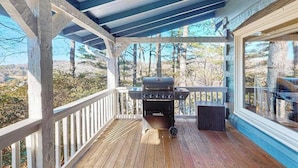 A covered outdoor deck with a grill, wooden railings, and a view of trees and hills. - Treehouse Retreat Stay (Sky Valley)