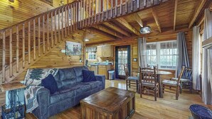 A wooden interior with a sofa, coffee table, and dining area. - Bear's Den Sautee Cabin (Sautee Nacoochee)
