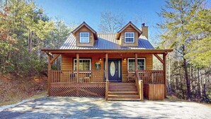 A log cabin with a porch, a chimney, and a front door. - Bear's Den Sautee Cabin (Sautee Nacoochee)