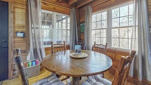 A wooden cabin interior with a round dining table, four chairs, and large windows. - Bear's Den Sautee Cabin (Sautee Nacoochee)