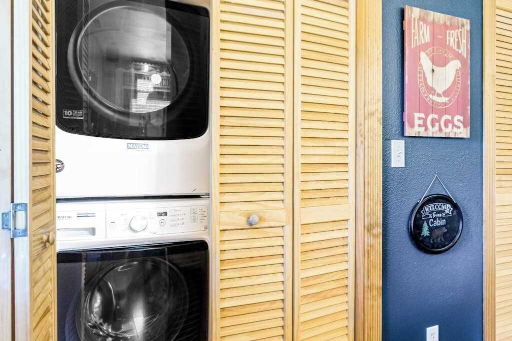 A laundry room with a washing machine, dryer, and wooden slatted walls.