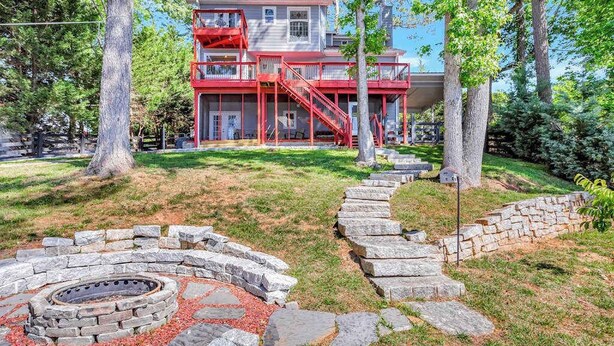 Un edificio de dos plantas con fachada roja, rodeado de árboles y un hogar de piedra.