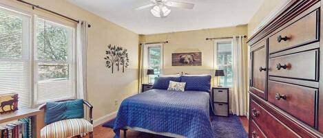 A bedroom with a bed, a chair, a dresser, and a ceiling fan.