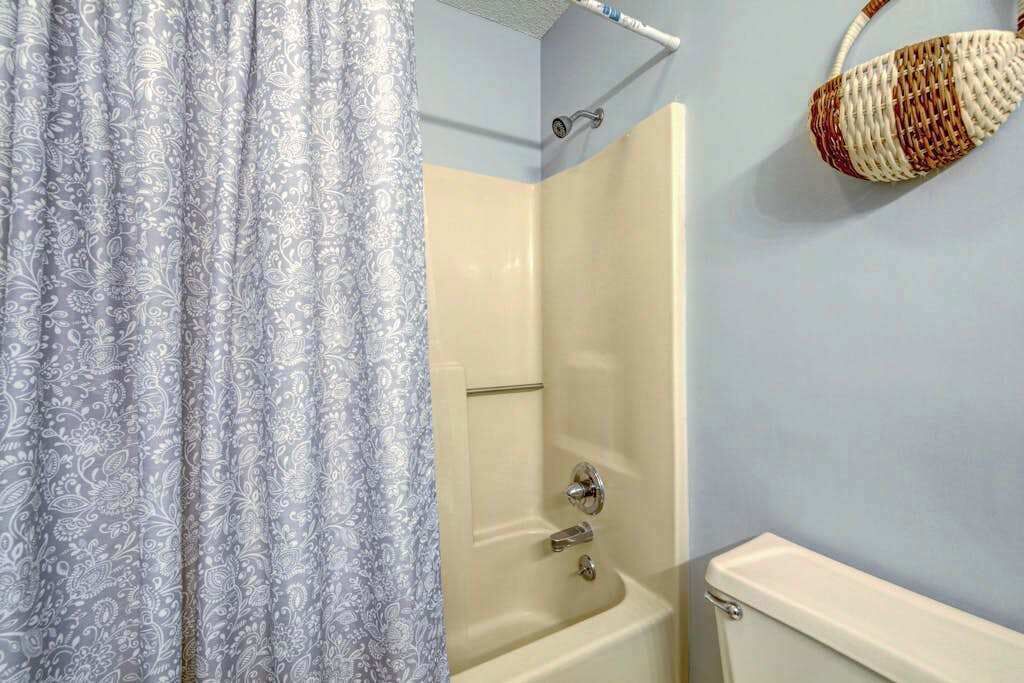 Une salle de bain équipée d’une douche, de toilettes et d’un panier fixé au mur.