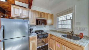 A kitchen with wooden cabinets, a stainless steel refrigerator, a stove, and a window with blinds. - Paradise Retreat Mountainview (Jasper)