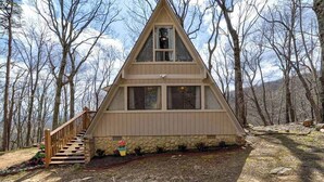 A triangular wooden cabin with a staircase and a stone foundation, surrounded by trees. - Paradise Retreat Mountainview (Jasper)