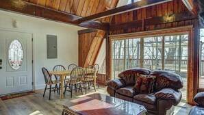 A wooden interior with a dining table, chairs, a leather sofa, and large windows. - Paradise Retreat Mountainview (Jasper)