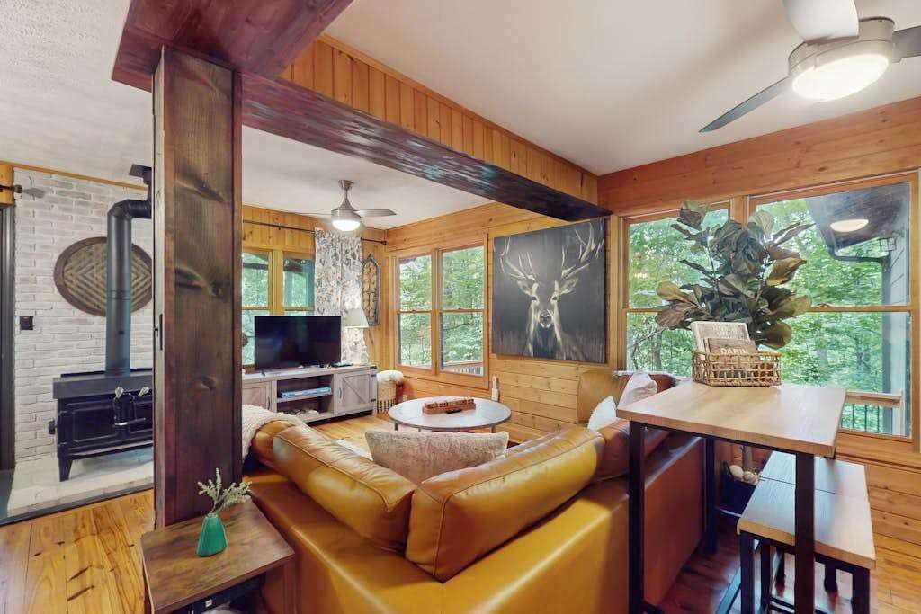 Ein gemütliches Blockhaus mit Kamin, Ledersofa, Esstisch aus Holz und großen Fenstern.