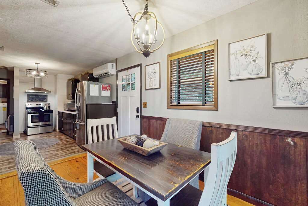 Uma sala de jantar com mesa de madeira, cadeiras e um candelabro.