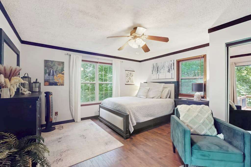 Une chambre à coucher avec un lit, une chaise, un ventilateur de plafond et une fenêtre.