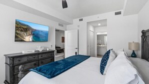 Ein Schlafzimmer mit einem Bett, einem Schminktisch, einem Fernseher und einem Deckenventilator.