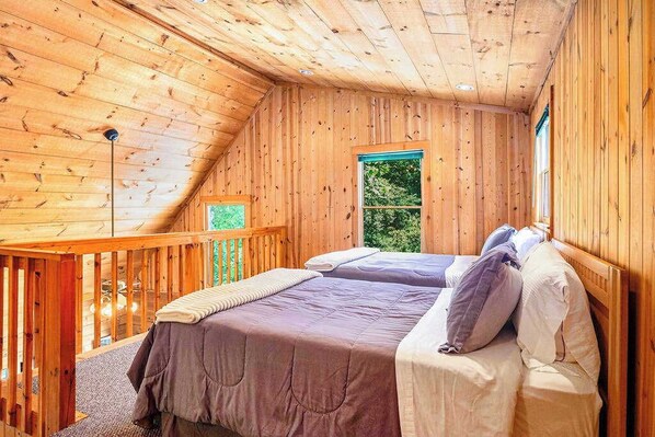 Een houten hutje met twee bedden, een balkon en een raam.