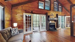 A spacious room with a wooden ceiling, a fireplace, a sofa, and a dining table.