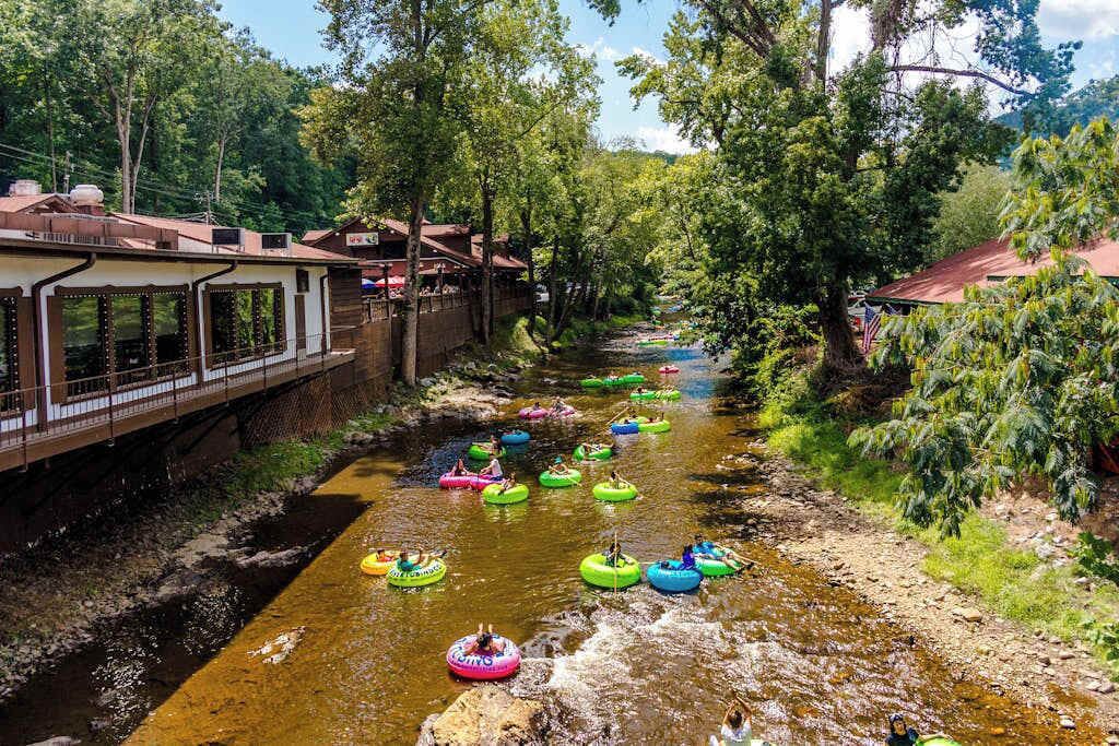 A river with people on inflatable tubes, a bridge, and buildings on the banks.